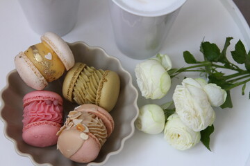 Breakfast with colorful macaroons on the plate, white cup and white roses