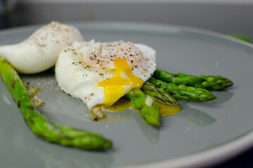 Breakfast and brunch ideas: poached eggs with asparagus in a plate with rye bread, top view