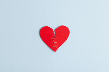 Red ripped paper cut heart on pastel blue background. Creative Valentine's Day idea with torn heart on minimal background, top view