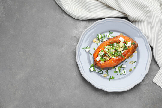 Tasty cooked sweet potato with feta cheese, pumpkin seeds and green onion on grey table, top view. Space for text