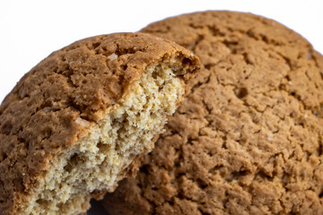 Two oatmeal cookies on a white background: one broken in half to reveal its soft, chewy center, while the other is blurred in the background, highlighting the texture and warmth of homemade treats