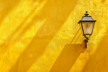 Traditional wrought iron outdoor light attached to a plain yellow exterior wall