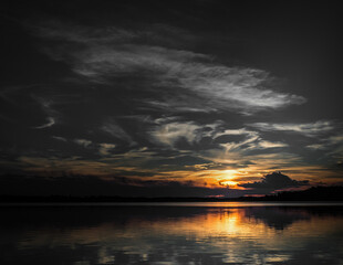 Obraz premium A mesmerizing sunset over a peaceful lake, featuring dramatic clouds and a golden reflection on the still waters