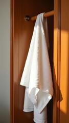 Clean white towels neatly hanging on a wooden rack illuminated by soft sunlight