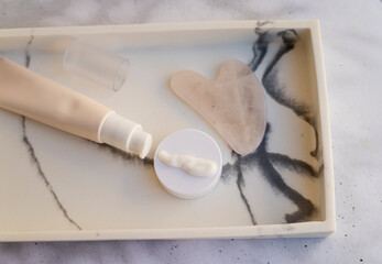 Anti-Age Eye Cream and Gua Sha Stone in a marble plate