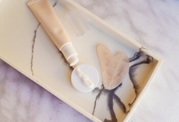 Anti-Age Eye Cream and Gua Sha Stone in a marble plate