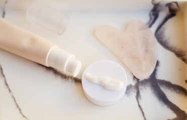 Fototapeta premium Anti-Age Eye Cream and Gua Sha Stone in a marble plate