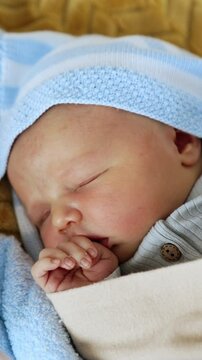 Adorable baby sleeping peacefully in the crib. Newborn child in blankets sleeps holding hand at his mouth. Top view close up. Vertical video