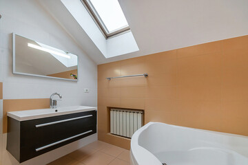 A modern bathroom, decorated in pastel colors, in the attic of a country house. Stylish .furniture, large corner bath.
