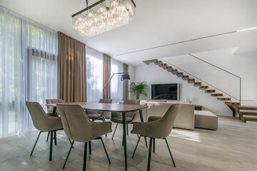 Luxury apartments with panoramic windows and stylish interior design. Beautiful ceiling .light above the dining table, stairs to the second floor.