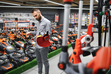 happy customer with electric lawn trimmer in hands at garden equipment store