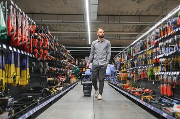 male builder in a hardware store chooses a tools