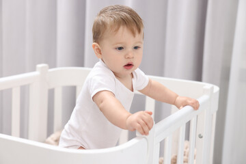 Cute little baby in crib at home