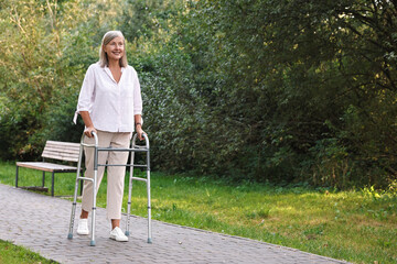 Senior woman with walking frame in park, space for text