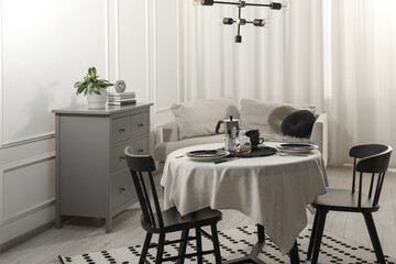 Stylish table setting with beautiful dishware and black chairs in dining room