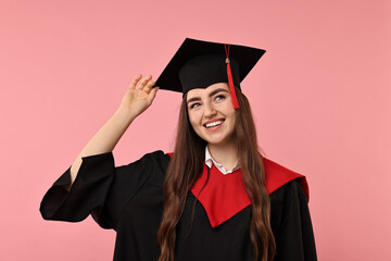 Happy student after graduation on pink background