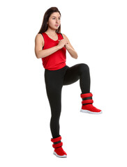 Woman in sportswear exercising with ankle weights on white background