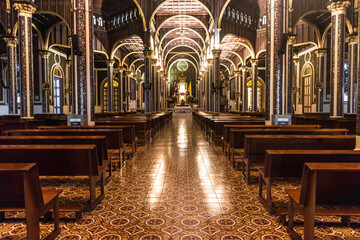 Wide central hallway with classical architecture with wooden benches from the Basilica of Our Lady of the Angels in Cartago, Costa Rica
