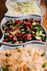 Three White Bowls with Assorted Fresh Dishes on Wooden Surface
