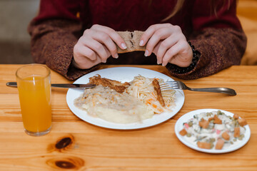 Person Holding Bread Over Meal with Mashed Potatoes and Salad