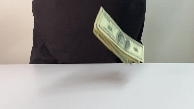 Hands are skillfully counting several bills, arranged neatly on a clean white surface, while additional banknotes appear to fall, enhancing the moment of financial focus.