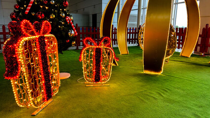 Illuminated Christmas decorations with glowing gift boxes and a festive tree, indoor setup,...