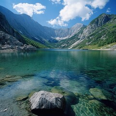 Serene mountain lake with crystal-clear water, surrounded by majestic peaks under a blue sky.