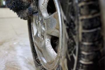 Cleaning car wheel thoroughly with brush and soap for maintenance and shiny result
