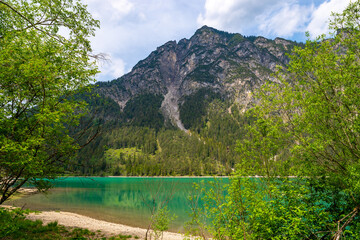 View over the turquoise colored Heiterwanger lake on a sunny day. The mountains are reflected in the smooth water of the lake. Heiterwang, Austria