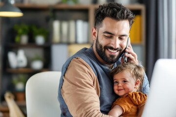 Caring father carrying baby boy while talking on mobile phone at desk in home office