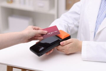 Woman paying with credit card via terminal at counter indoors, closeup