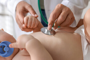 Pediatrician examining little child with stethoscope in clinic, closeup. Checking baby's health