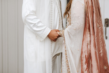 Intimate Wedding Moment Capturing Bride and Groom Holding Hands in Traditional Pakistani-Moroccan Attire