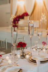 Elegant Wedding Table Setting with Floating Candles, Red Roses, Gold Chargers, and Glassware