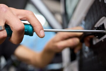 A closeup shot of a hand skillfully using a screwdriver on the intricate parts of a vehicle