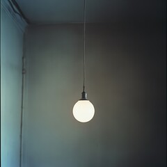 Single illuminated globe pendant lamp hanging in a room corner.