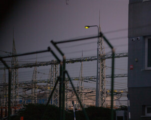 Electric substation equipped with security fencing and power lines, outdoor environment at dusk...