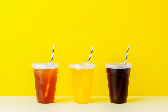 Three cups of different colored drinks with straws in them