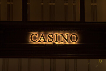 An illuminated casino sign radiantly mounted on the facade of a striking building, drawing attention and igniting interest in the nightlife
