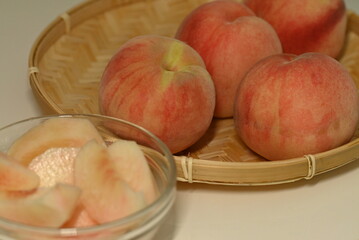 竹ざるにのせた桃とカットされた桃