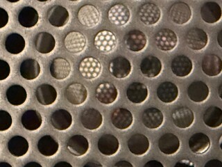 A close up view of a metal grill showcasing circular perforations creating an interesting geometric pattern and texture.