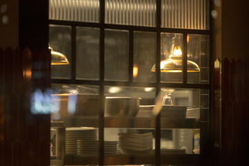 The interior view of a kitchen showcases an array of cooking equipment, neatly arranged plates, and a cozy atmosphere enhanced by warm lighting