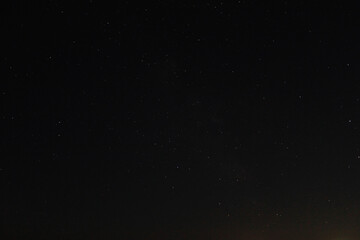 Bright glowing constellations and stars on a summer night in a clear dark sky with a slight orange...