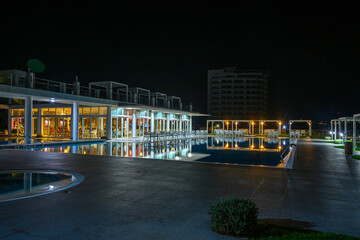 Fototapeta premium Tranquil evening by the poolside with reflections shimmering under the night sky