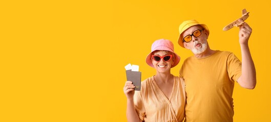 Mature couple of tourists with passports and wooden airplane on yellow background with space for text