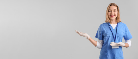 Female intern showing something on grey background