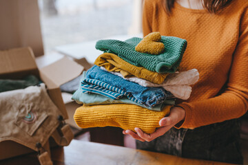 Close-up of female hands holding a fabric heart and clothes for charity