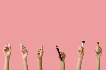Female hands with bottles of makeup foundation, brushes and sponge on pink background