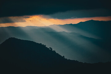Dramatic sunlight breaking through clouds mountain range landscape photography natural environment wide angle serenity and reflection