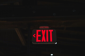 red light up exit sign with arrow in a dark room